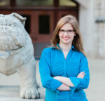 photo of Hannah Stigter standing next to the stone bulldog statue on Butler's campus