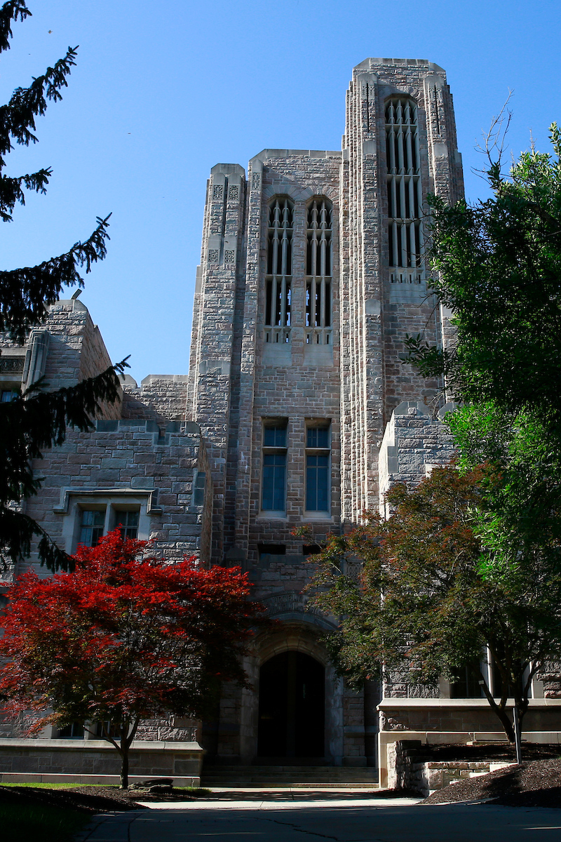 limestone building with trees in reds and greens in front