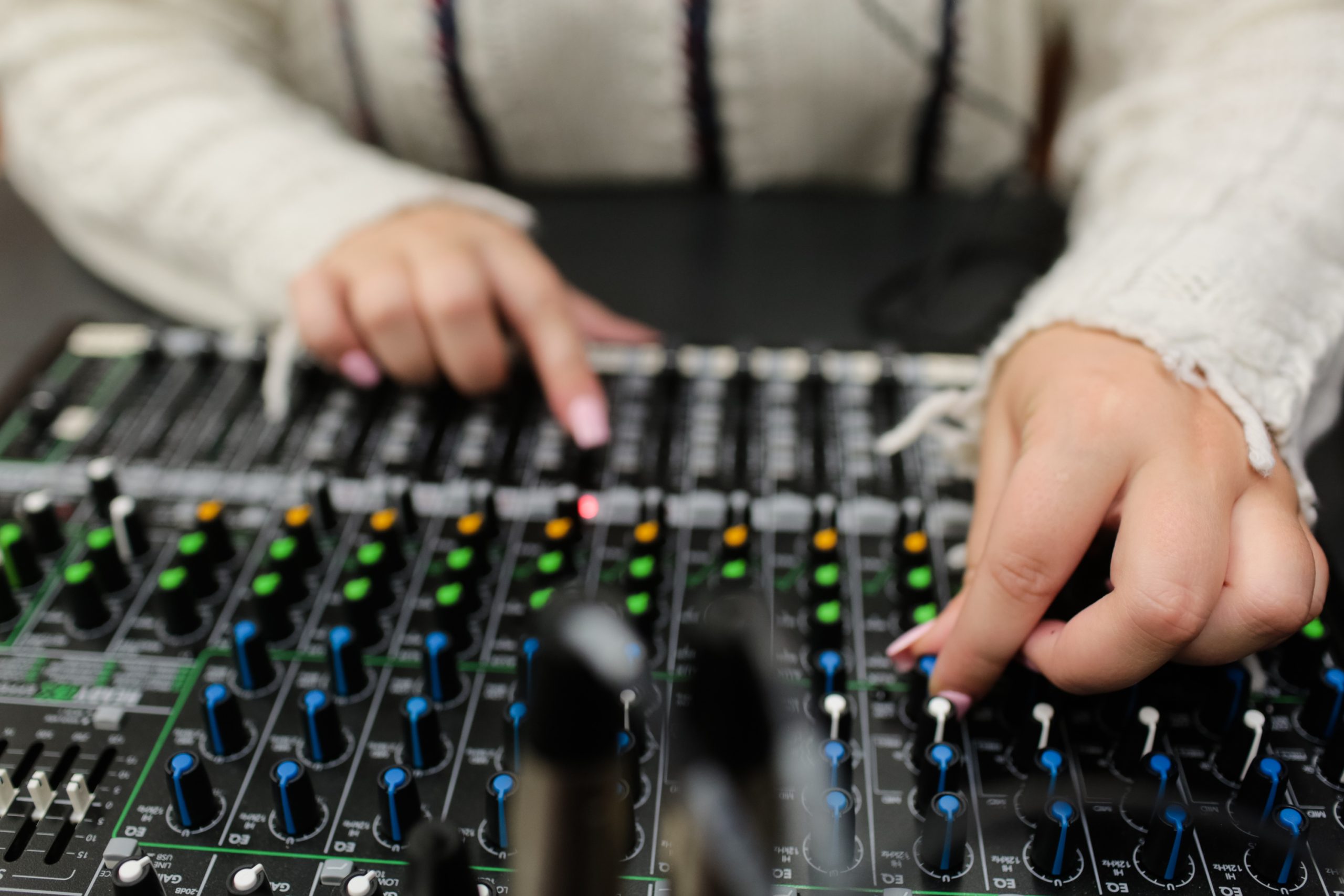 hands sliding controls on a mixing board