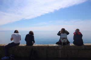 students sitting on a ledge looking at the ocean