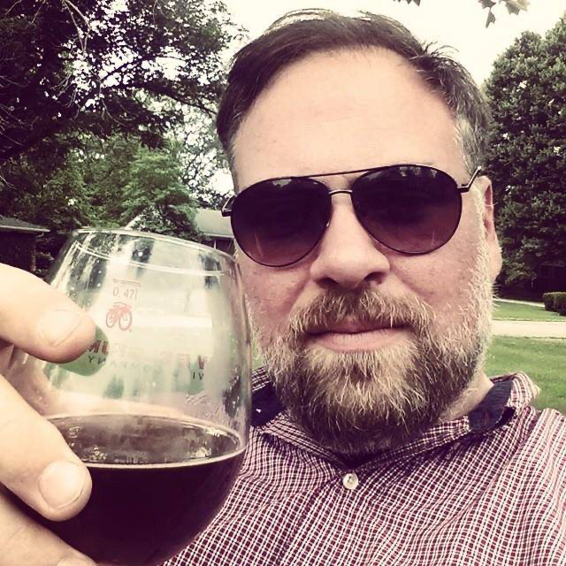 Brent Hege male with brown hair, beard, sunglasses, glass of wine