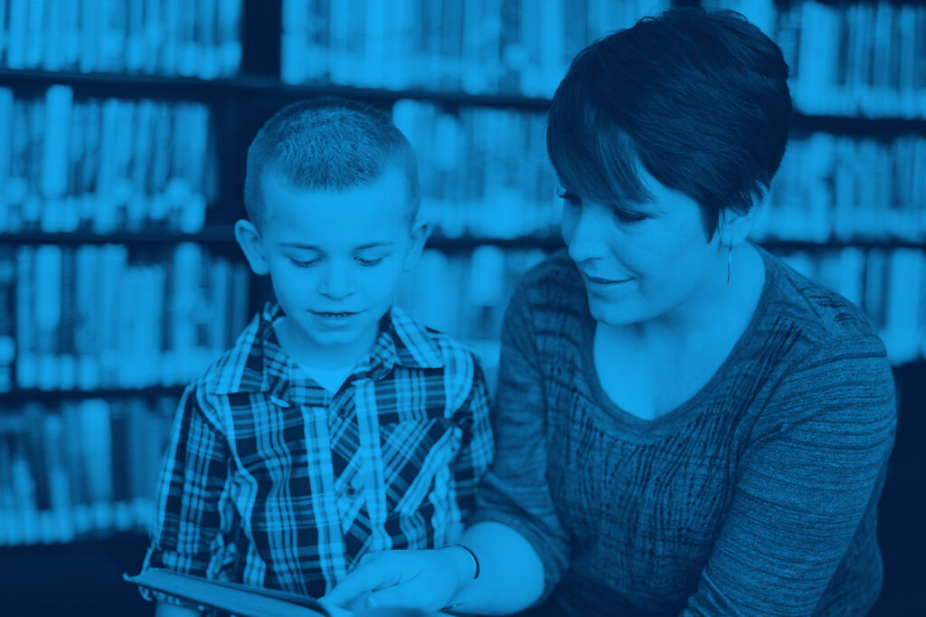 A teacher sitting next to a young student.