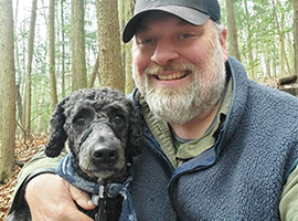 Brent Hege with dog out in wooded area