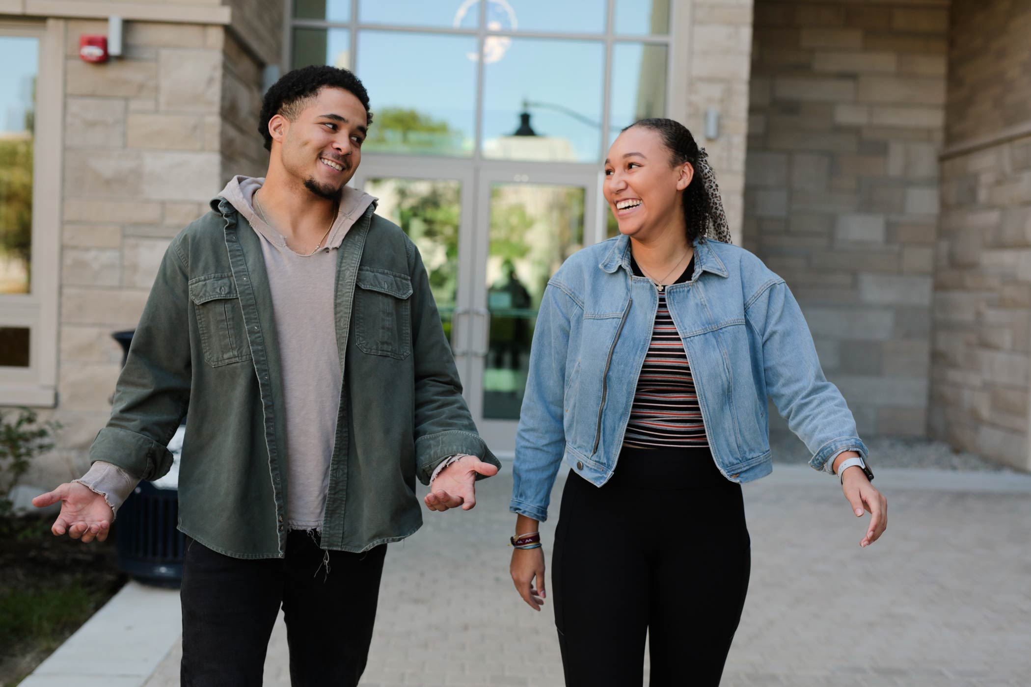 Two students smile at each other while they walk through campus