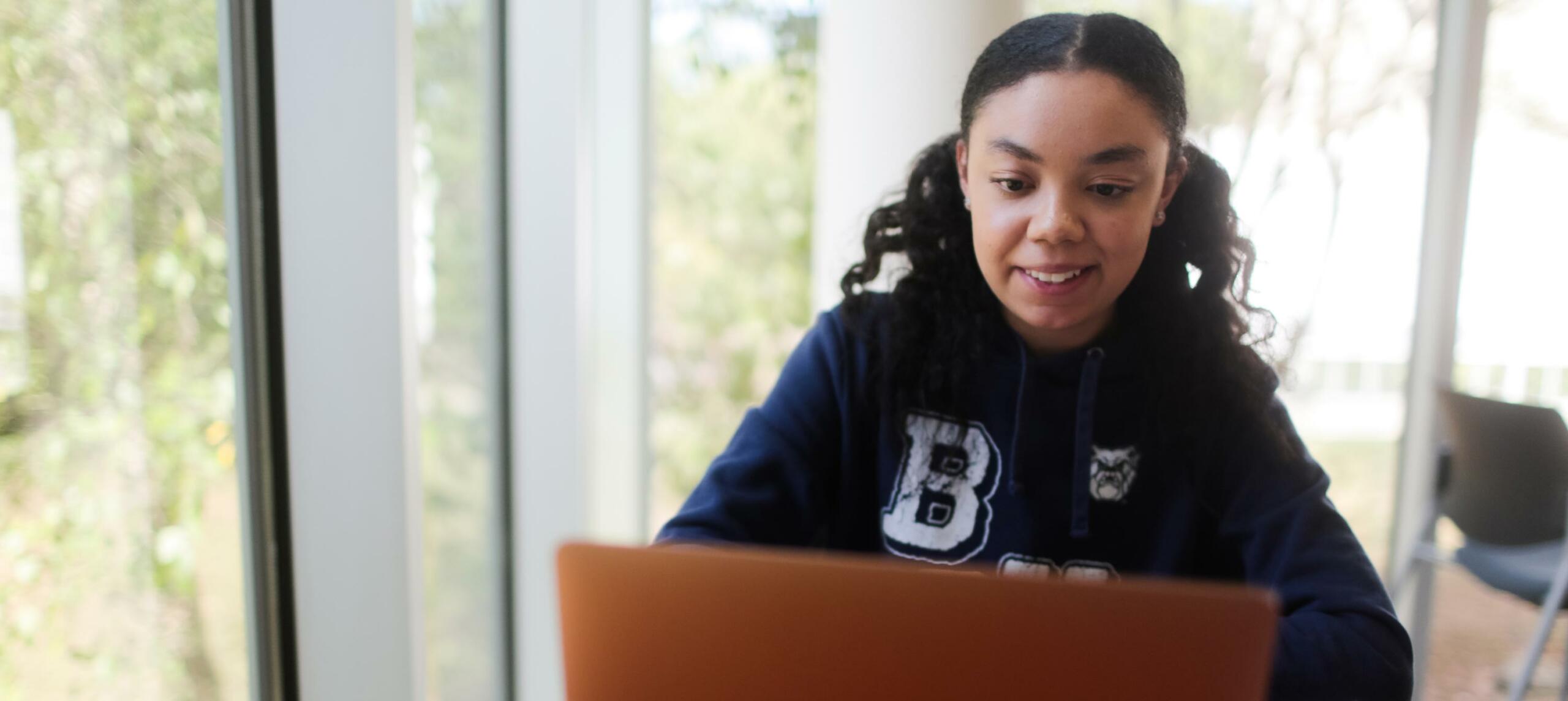 Student in Butler sweatshirt looks at laptop
