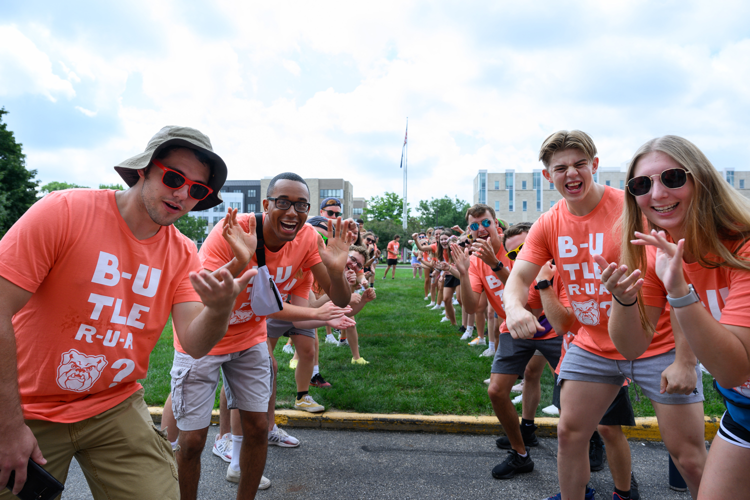 student orientation guides in matching orange shirts forming a tunnel for new students to run through