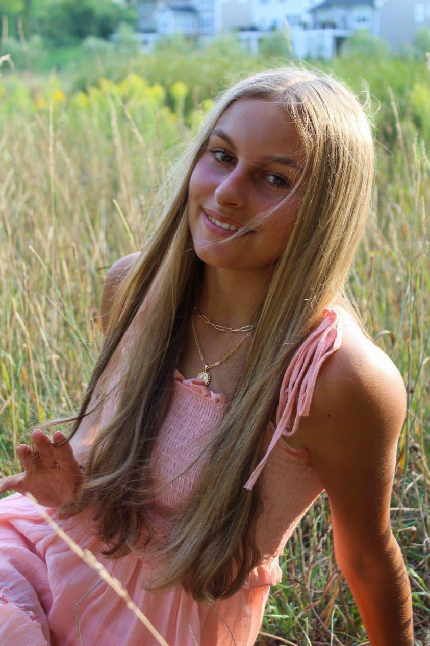 Women sits in a field of grass smiling