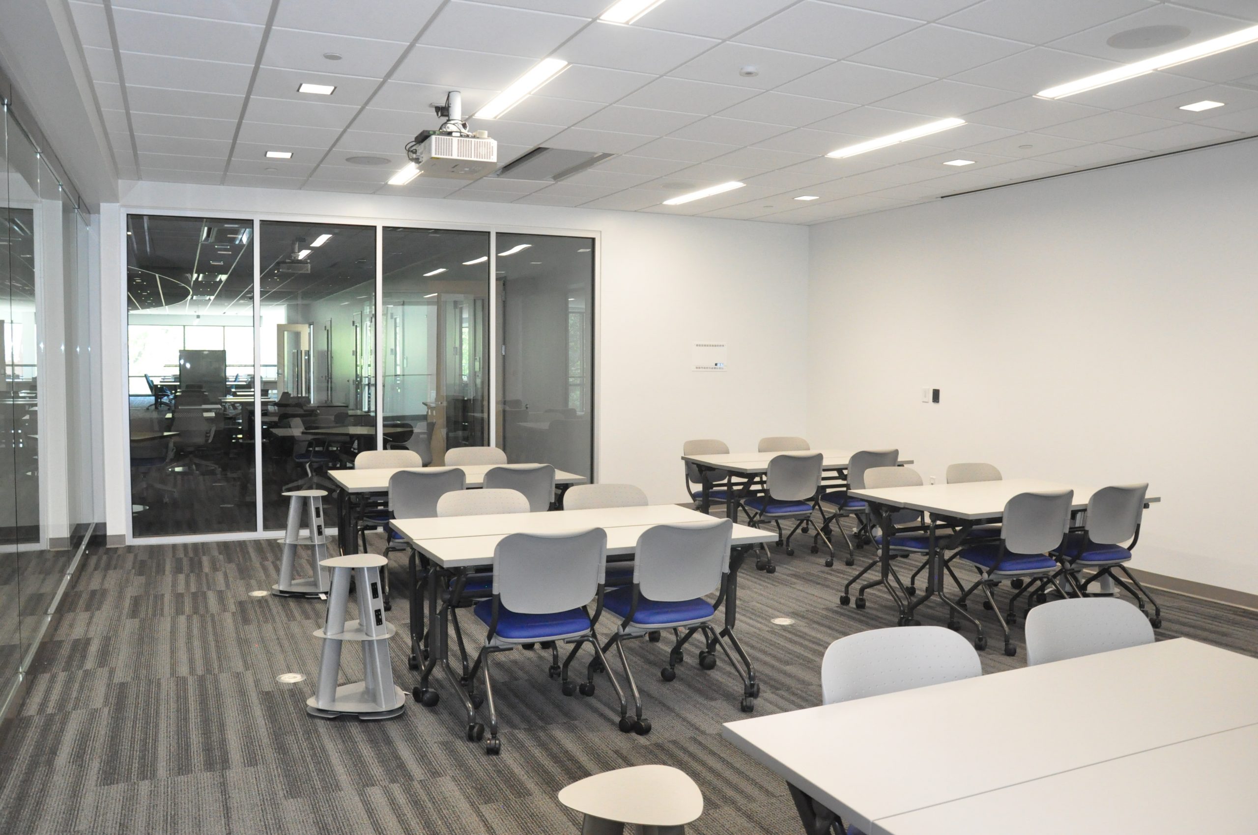 A collaborative workspace in the new Sciences Complex, filled with rolling tables and chairs, as well as many power outlets for devices throughout the room
