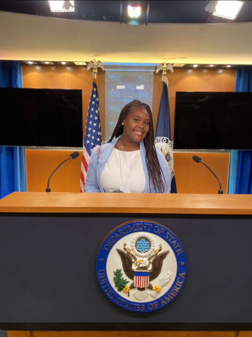 A woman stands behind a podium at the Department of State