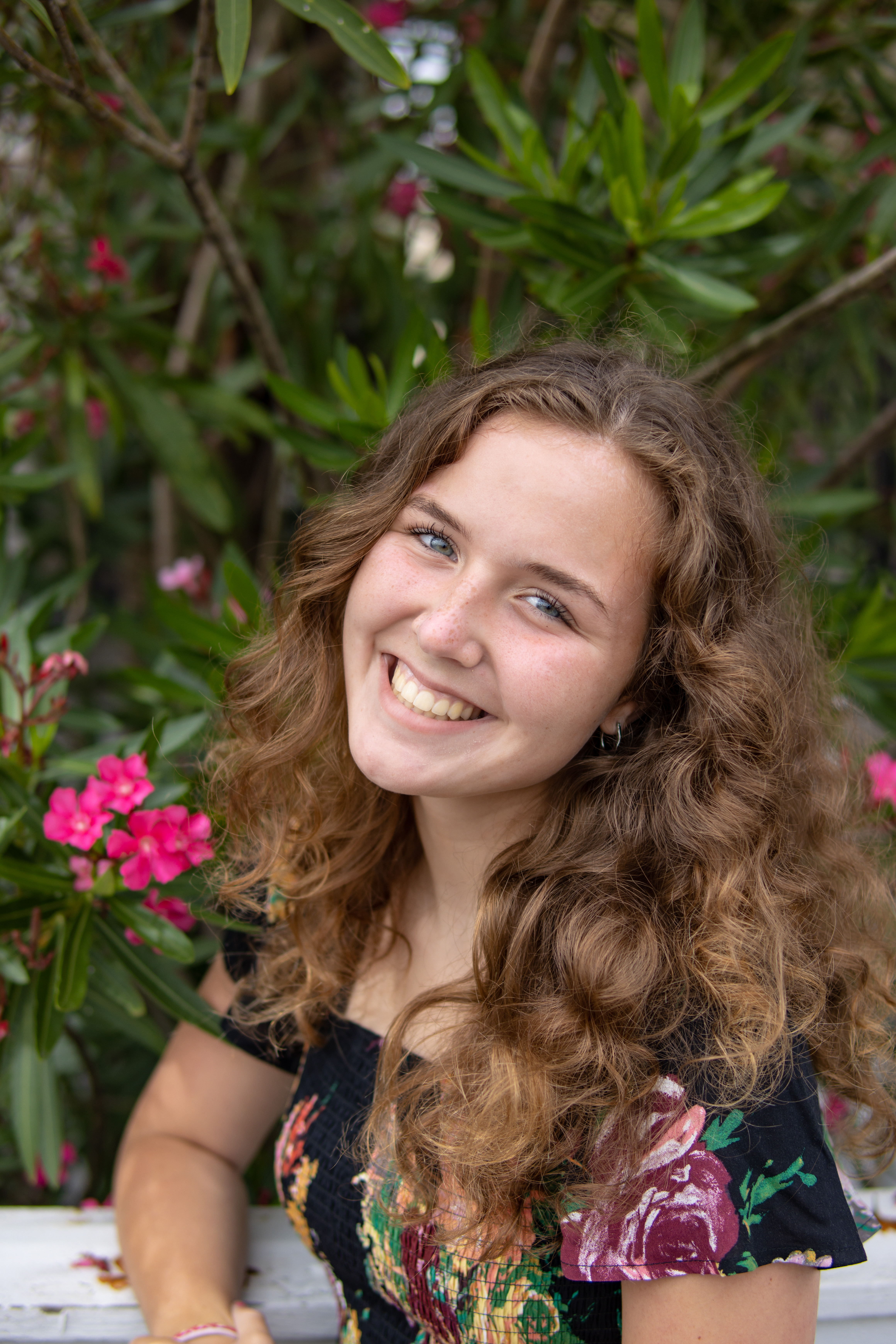 A female student stands in front of flowers smiling