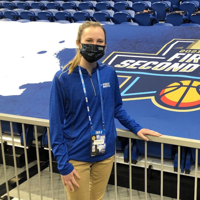 Student standing in front of an NCAA sign in an arena