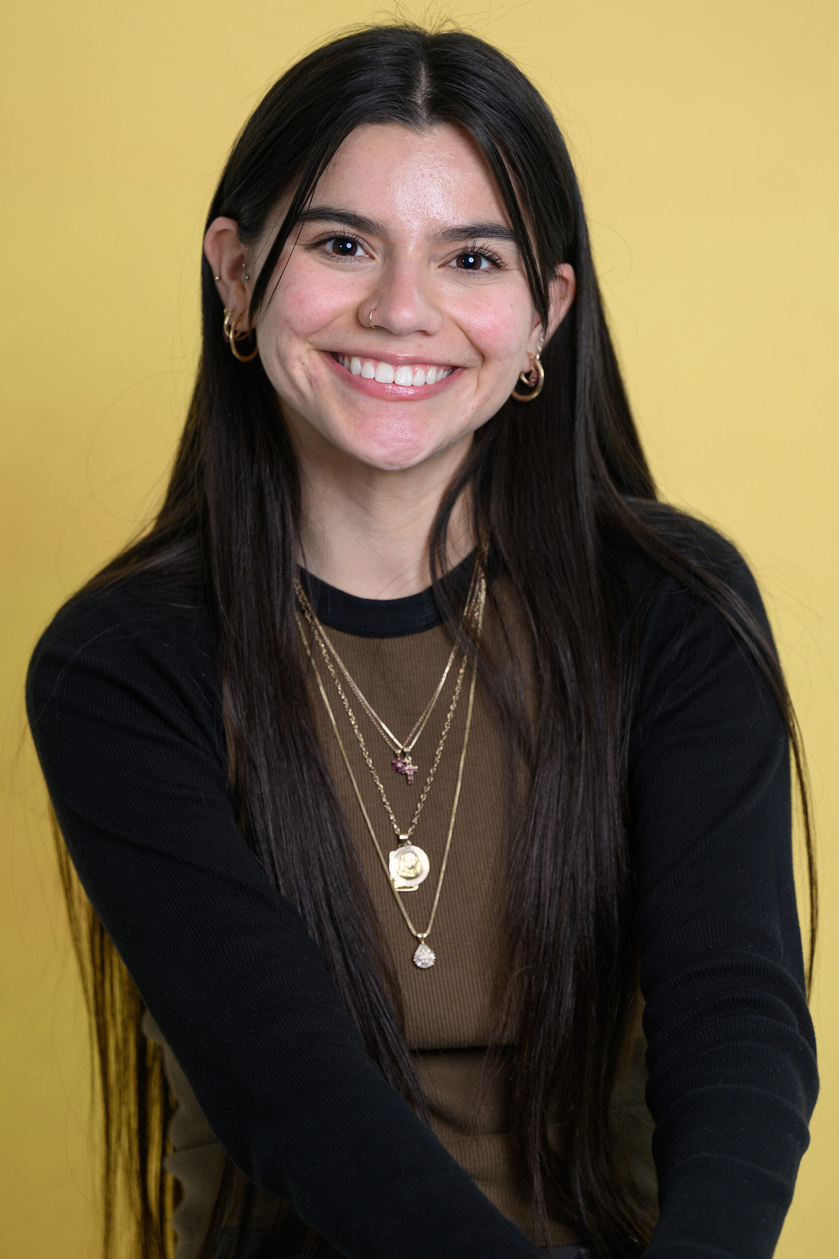 A female student is smiling in front of a yellow background