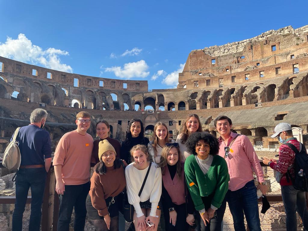A group of students stand in front of the Colosseum in Rome.
