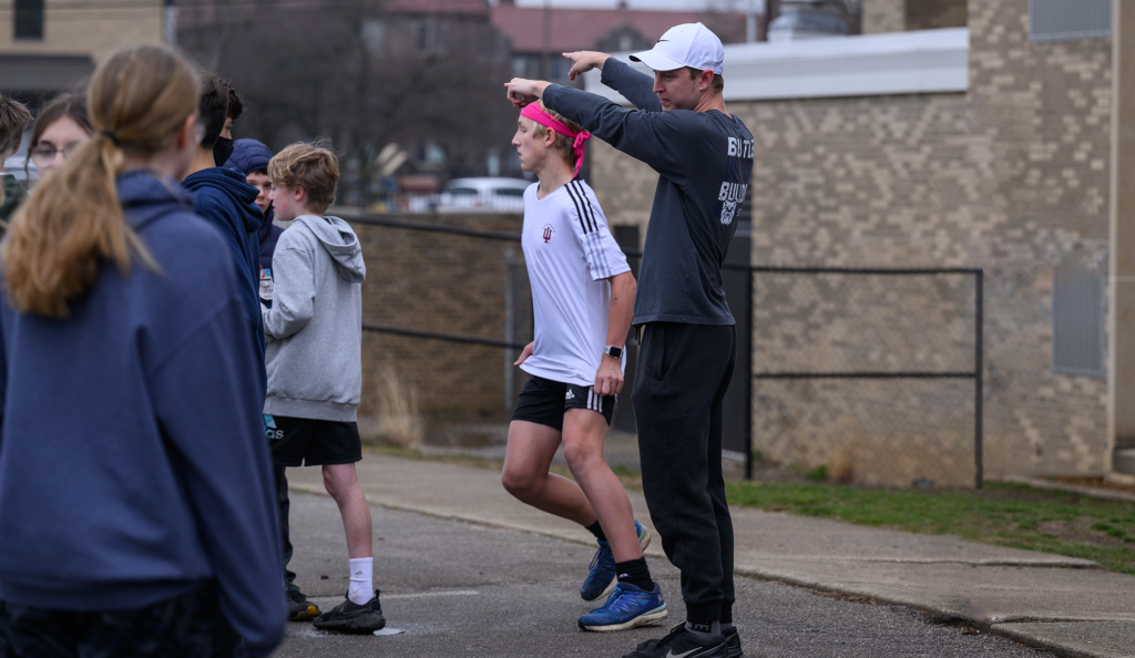 male and female young students playing soccer, college male in blue shirt and white hat