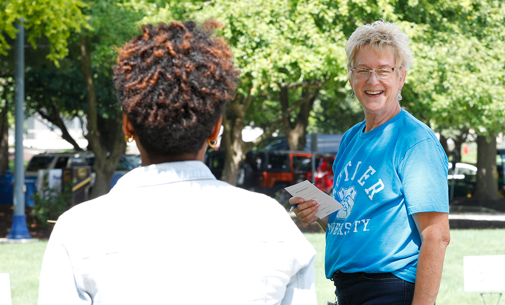 white haired woman in light blue t-shirt Butler University smiling at woman in white jacket, brown hair
