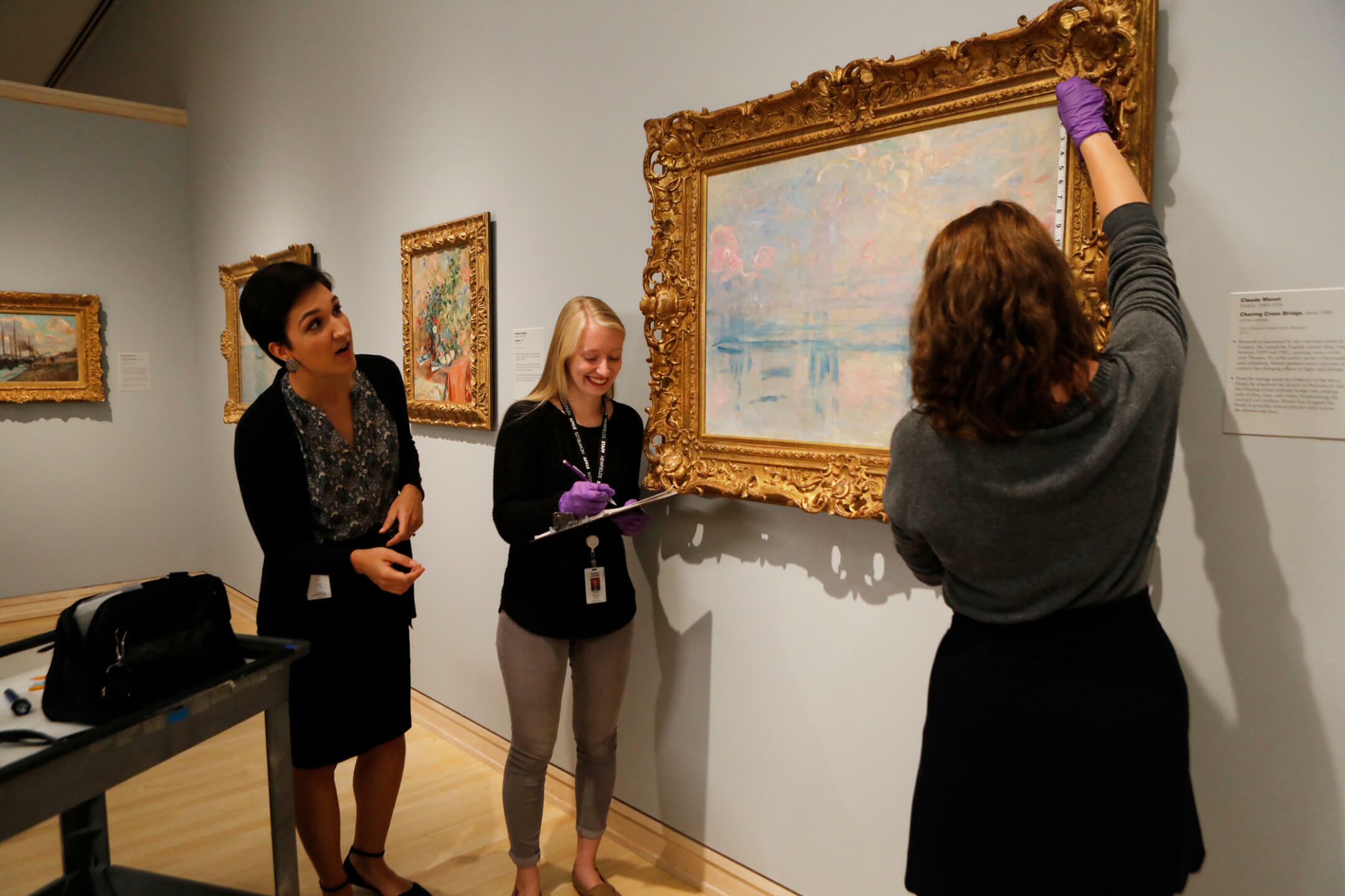 students measuring a painting with purple gloves on
