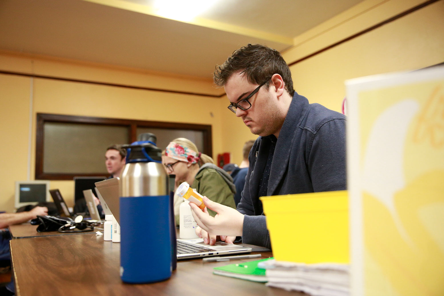 Pharmacy student examines medication container in classroom