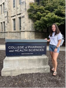 Hillary Reed standing next to the Pharmacy Building sign