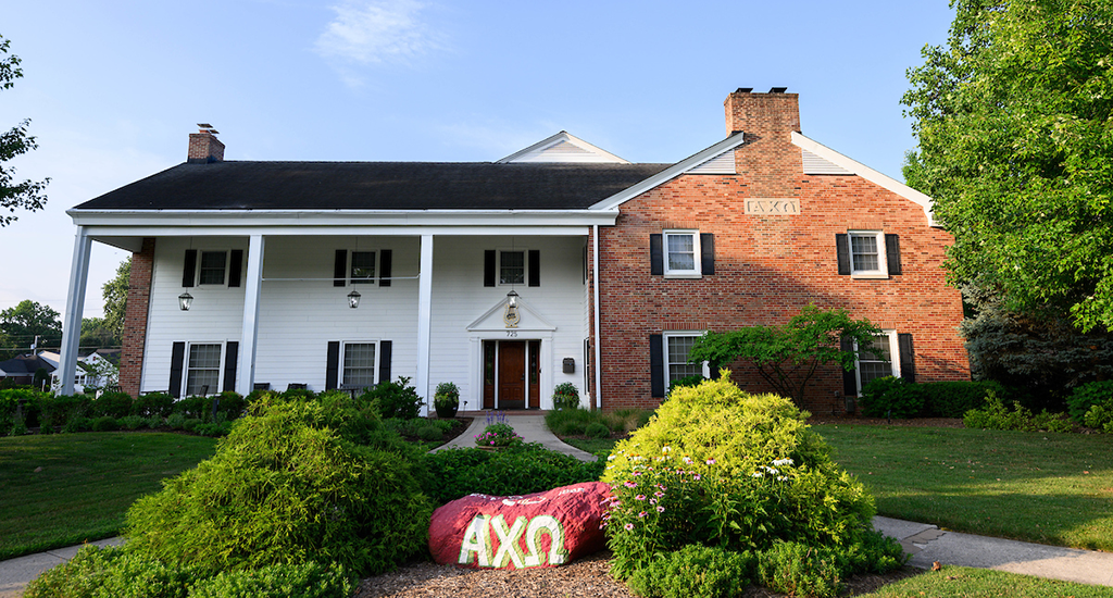 Alpha Chi Omega house. half red brick, half white , white pillars, red rock in front with greek letters