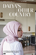 Dalya's other country. woman with pink head scarf and white shirt in kitchen with white cabinets.