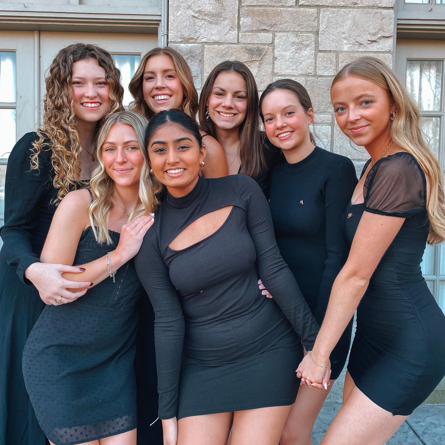 7 members in black dresses in front of Theta house