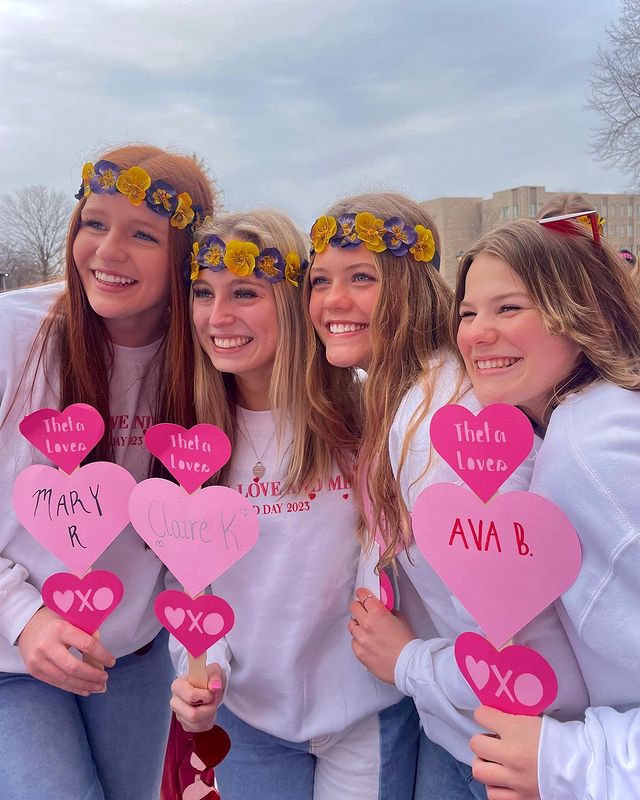 4 women on bid day hold heart signs with their names on them