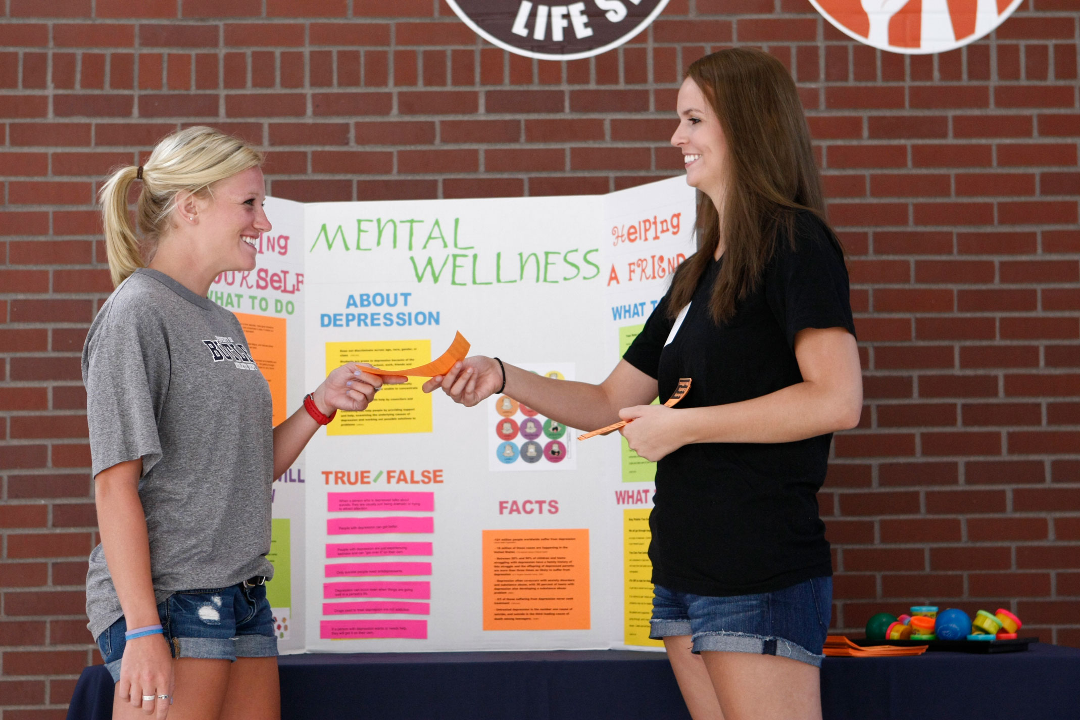 Staff member hands flyer to student at mental wellness event on campus
