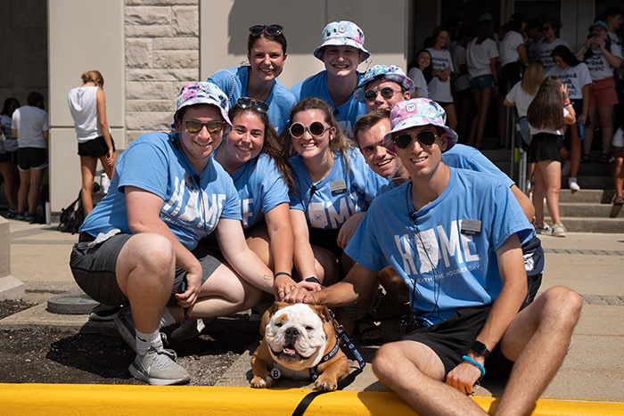 Student orientation guides wearing light blue shirts and bucket hats petting Blue the fourth
