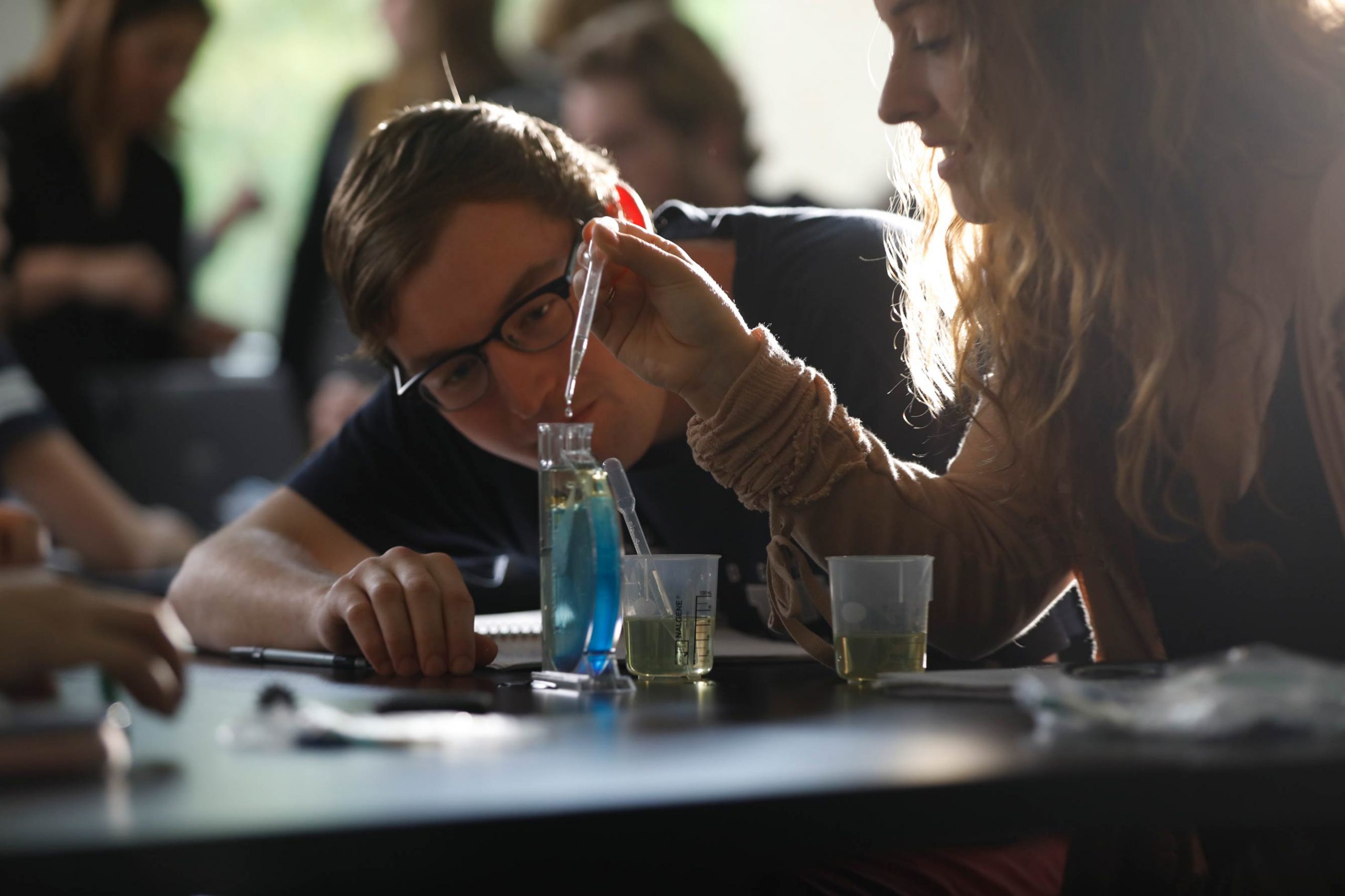 Two students work with beakers in a lab environment