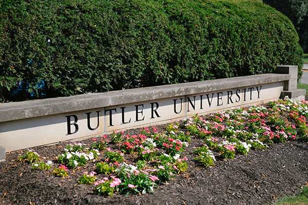 stone structure with butler University, flowers in front, green hedge behind it