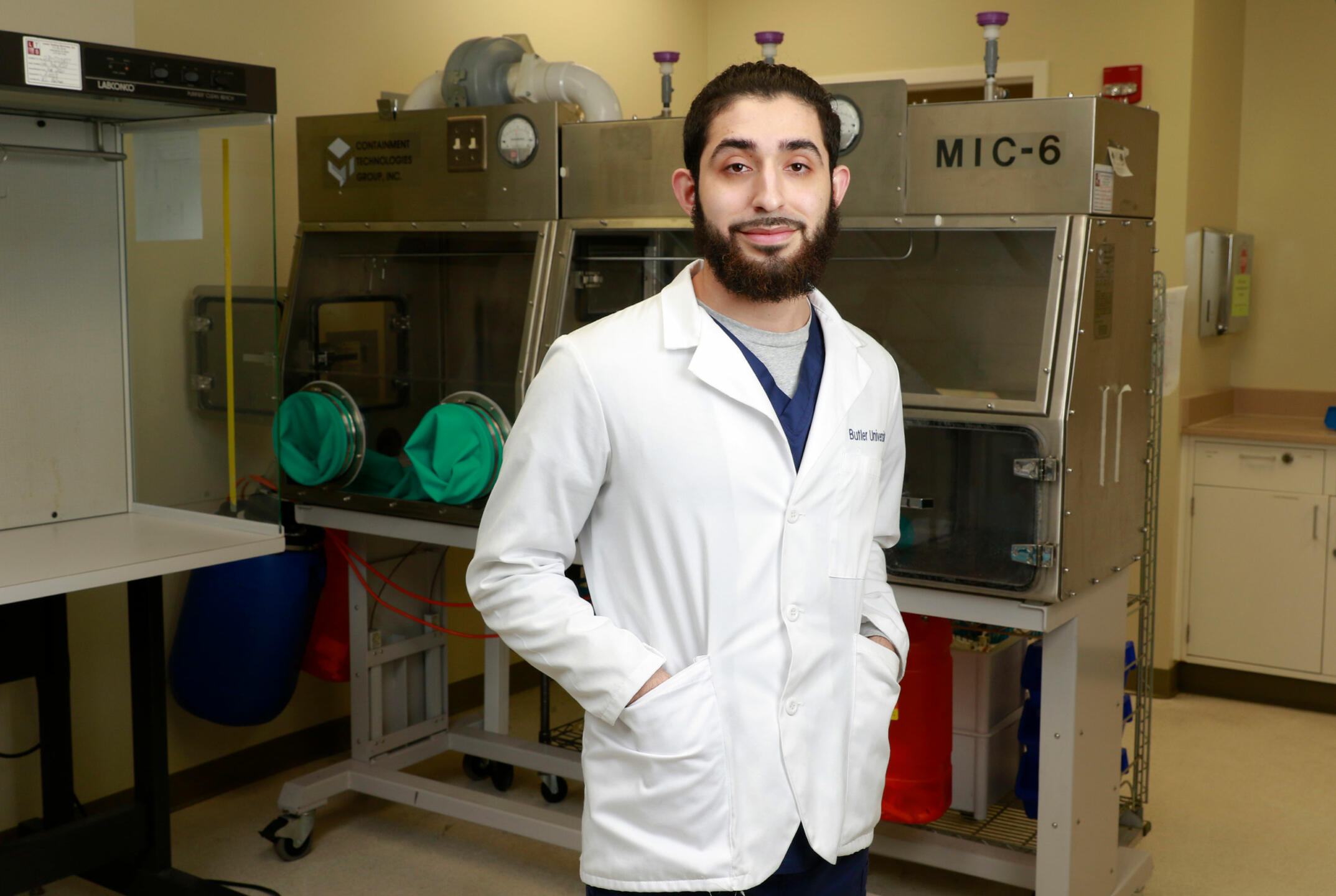Student in white lab coat poses in lab