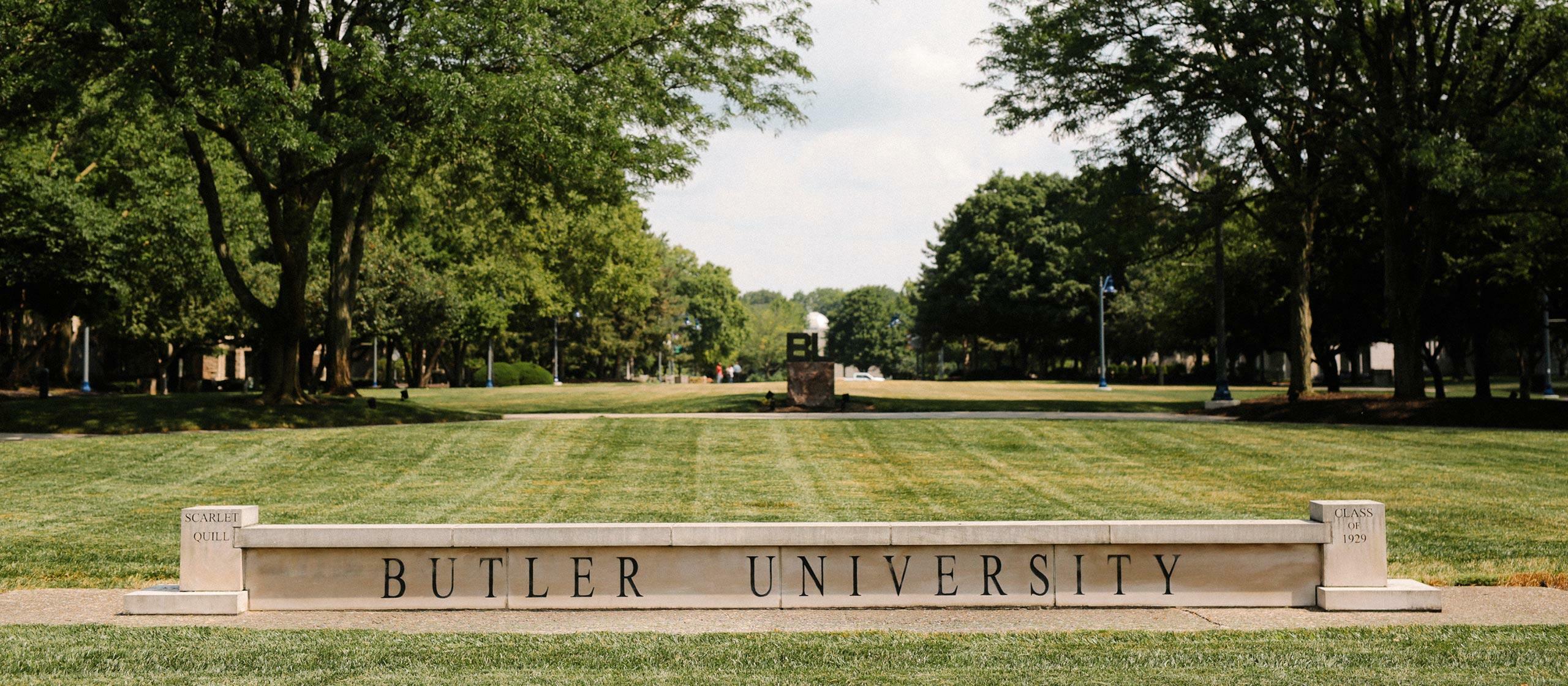 Large green grass lawn on Butler's campus with concrete sign of Butler University