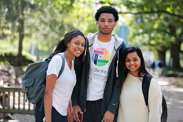 two female students with a male student in the middle wearing a BU Be Well shirt