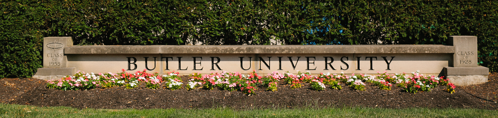 low stone wall with Butler University engraved and flowers in front