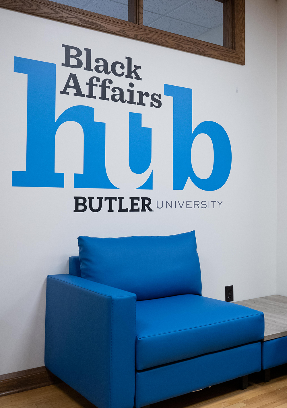 blue chair with Black Affairs Hub Butler University printed on wall behind it.