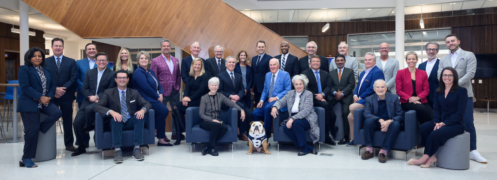 group of 29 men and women in business clothing posed in chairs and standing, with Butler live mascot bulldog