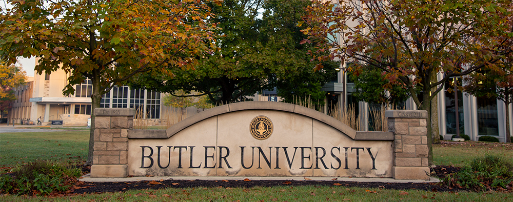 concrete sign with words Butler University and trees behind it